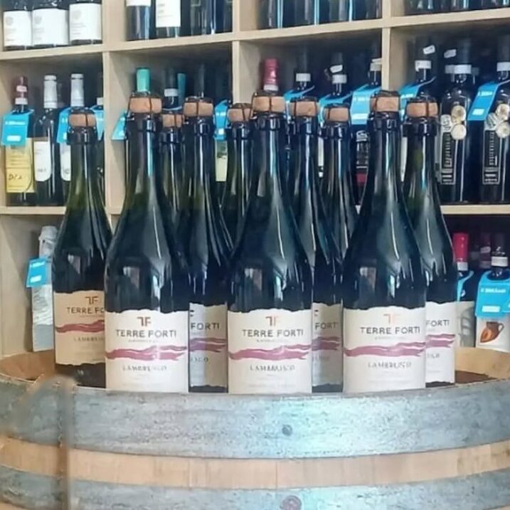 Bottiglie di Lambrusco Terre Forti su una botte nella bottega Il Bibitaio